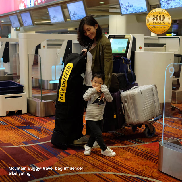 mère avec son enfant à l'aéroport avec ses bagages - Mountain Buggy travel bag  influenceur @kellynting